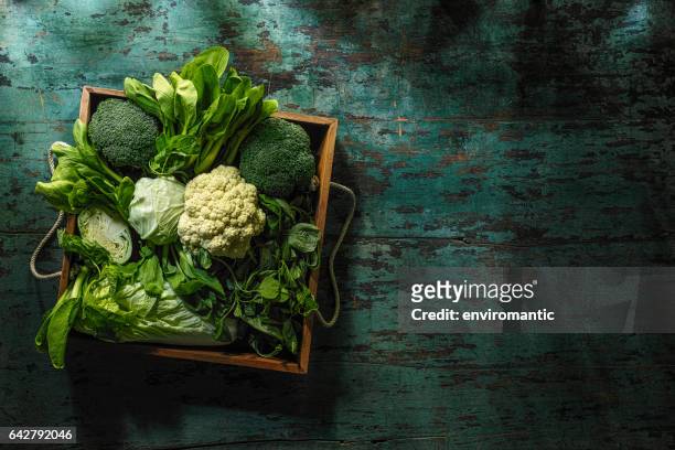 fresh green leaf vegetables in an old wooden crate on an old wooden turquoise table. - crucifers stock pictures, royalty-free photos & images