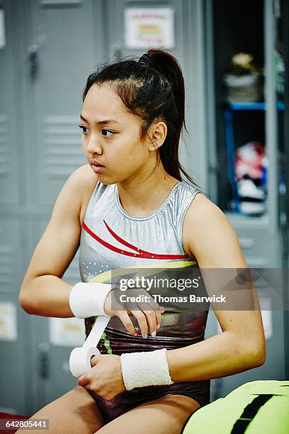 young female gymnast taping wrist before training - sports equipment locker stock pictures, royalty-free photos & images