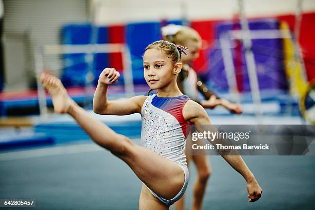 young gymnast doing warm-up exercises in gym - female gymnast balancing on one leg stock pictures, royalty-free photos & images