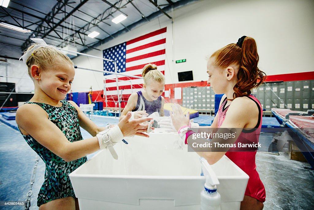 Gymnasts chalking hands during training session