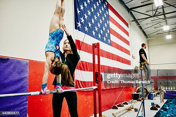 female coach adjusting handstand of gymnast on bar - prop sporting position stock pictures, royalty-free photos & images