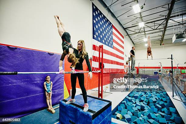 coach spotting gymnast on bars during training - barras paralelas barra de ginástica - fotografias e filmes do acervo