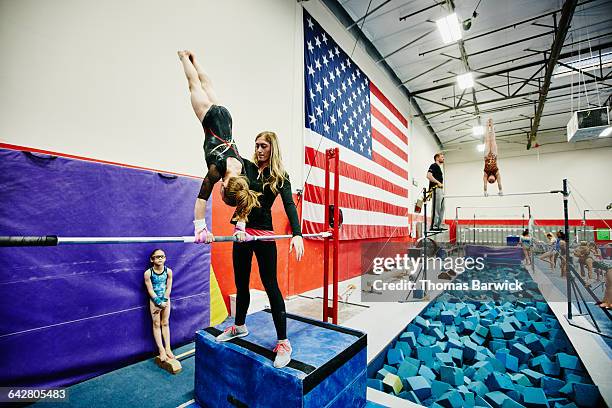 coach spotting gymnast on bars during training - parallel bars gymnastics equipment 個照片及圖片檔