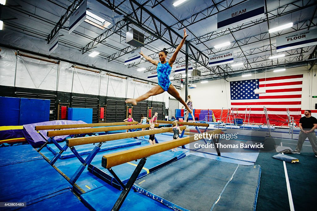 Female gymnast performing on balance beam in gym