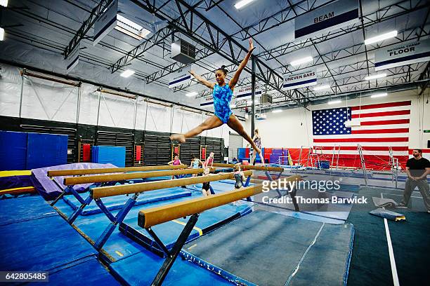Female gymnast performing on balance beam in gym
