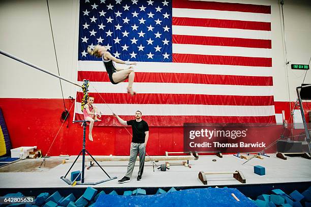 coach and gymnast watching teammate on high bar - usa gymnastics photos et images de collection