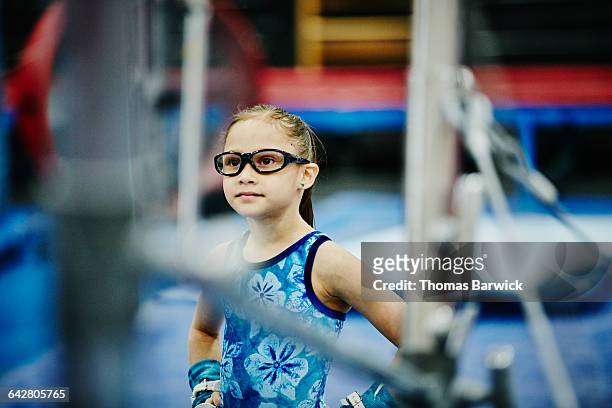 young gymnast watching teammate train on bars - kind brille stock-fotos und bilder