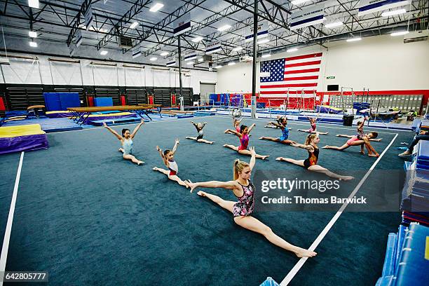 gymnasts doing splits in gym while warming up - jambes écartées photos et images de collection