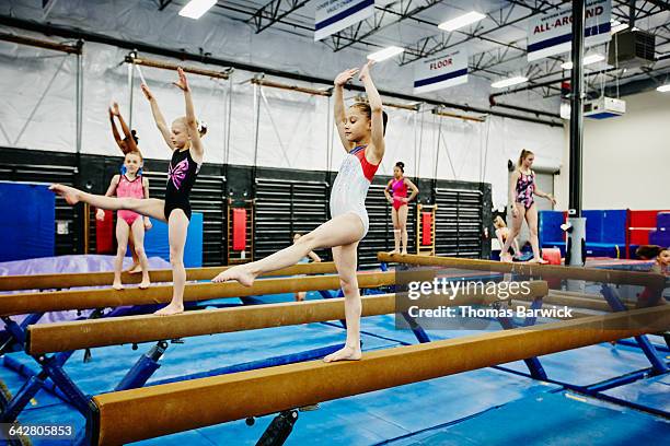 young female gymnasts practicing on balance beams - acrobat imagens e fotografias de stock