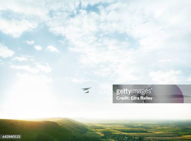 hang glider above green hills in cloudy blue sky - horizon over land imagens e fotografias de stock