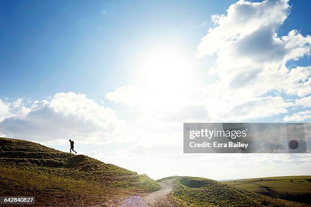 man hill running against a blue sky - distant hills stock pictures, royalty-free photos & images