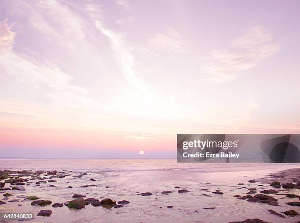 sunset over sea on rocky beach - tranquility rocks stock pictures, royalty-free photos & images