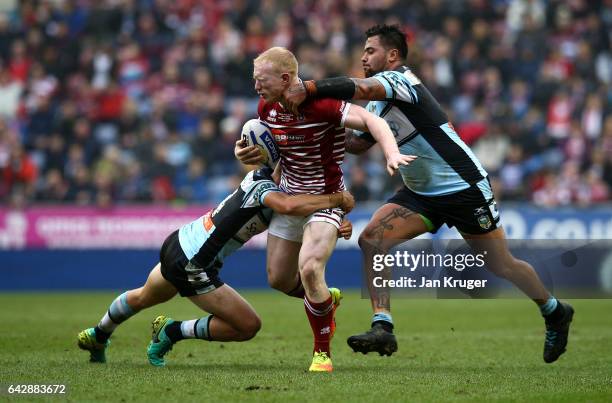 Liam Farrell of Wigan Warriors is tackled by Andrew Fifita of Cronulla-Sutherland Sharks during the Dacia World Club Challenge match between Wigan...