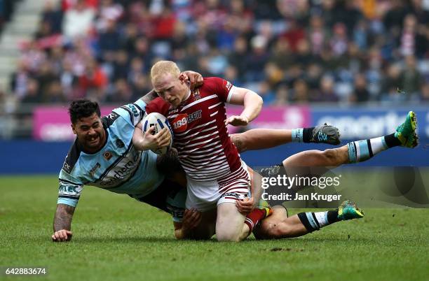 Liam Farrell of Wigan Warriors is tackled by Andrew Fifita of Cronulla-Sutherland Sharks during the Dacia World Club Challenge match between Wigan...