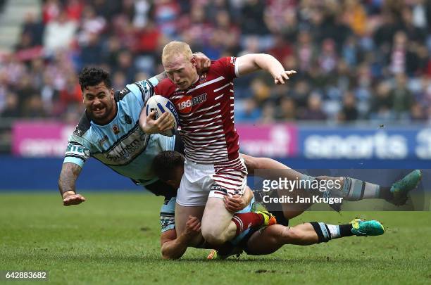 Liam Farrell of Wigan Warriors is tackled by Andrew Fifita of Cronulla-Sutherland Sharks during the Dacia World Club Challenge match between Wigan...