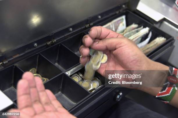 An employee handles Kenyan shilling currency coins at a cash desk inside a Nakumatt Holdings Ltd. Supermarket in Nairobi, Kenya, on Saturday, Feb....