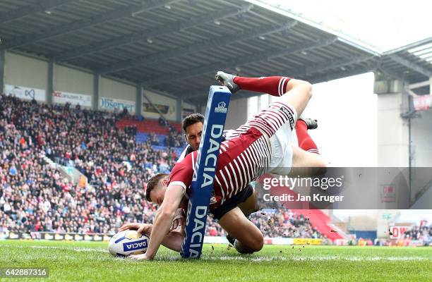 Joe Burgess of Wigan Warriors goes over for the opening try under pressure from Jesse Raimen of Cronulla-Sutherland Sharks during the Dacia World...