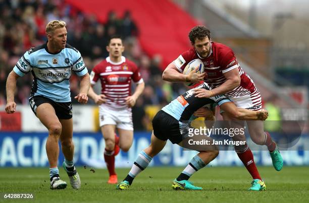 Sean O'Loughlin of Wigan Warriors is tackled by Jayden Brailey of Cronulla-Sutherland Sharks during the Dacia World Club Challenge match between...