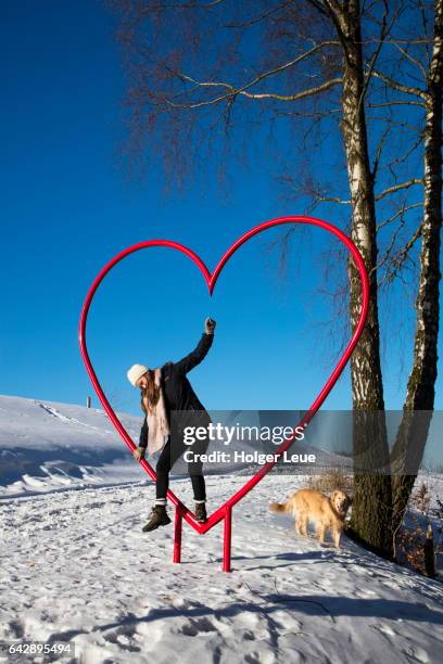 girl climbs red heart at liebesweg in winter - rhön stock-fotos und bilder