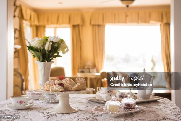 bereid engelse thee en scones in woonkamer - english tea room stockfoto's en -beelden