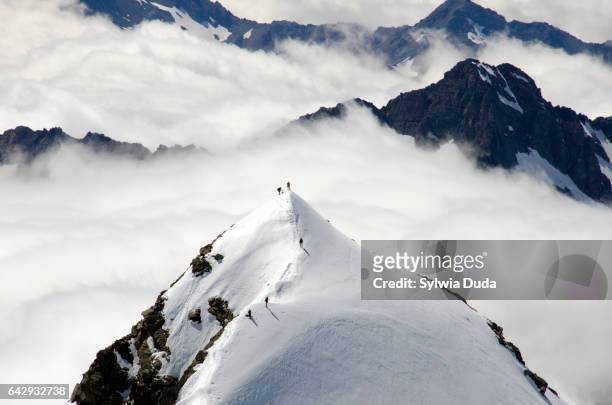 silhouette man on the snowy summit above clouds - bergsteiger gipfel stock-fotos und bilder