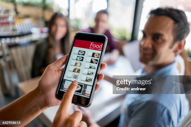cameriera che tiene il menu online su uno smartphone - waitress foto e immagini stock