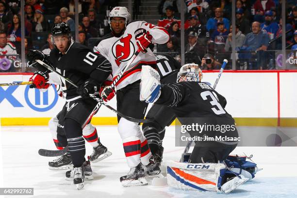 Jean-Francois Berube of the New York Islanders makes a save in front of Alan Quine and Devante Smith-Pelly of the New Jersey Devils at the Barclays...