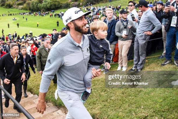 Dustin Johnson smiles with his son Tatum as he leaves the 18th hole green after his five stroke victory during the final round of the Genesis Open at...