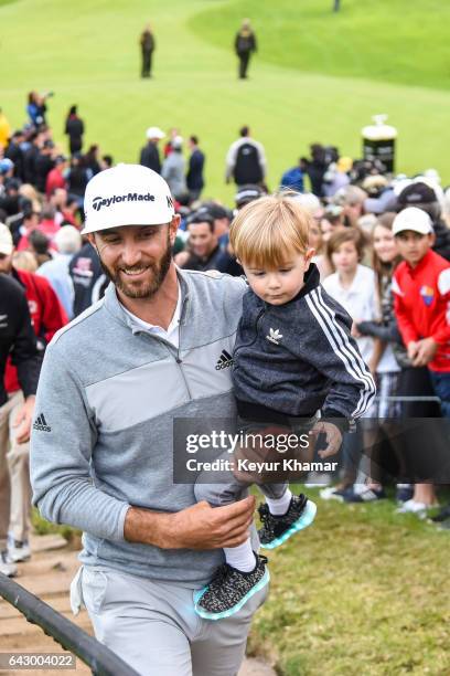 Dustin Johnson smiles with his son Tatum as he leaves the 18th hole green after his five stroke victory during the final round of the Genesis Open at...