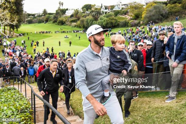Dustin Johnson smiles with his son Tatum as he leaves the 18th hole green after his five stroke victory during the final round of the Genesis Open at...