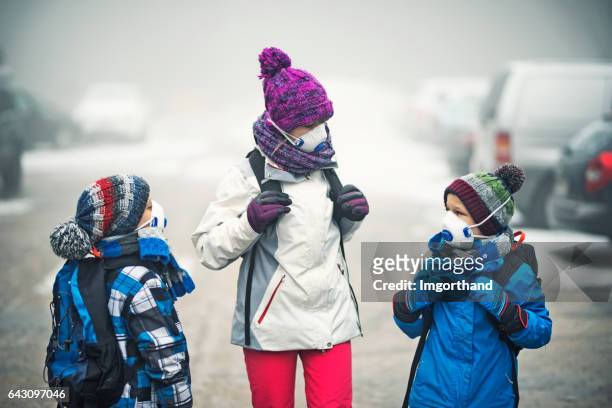 kinder gehen zur schule im smog - pollution masks stock-fotos und bilder