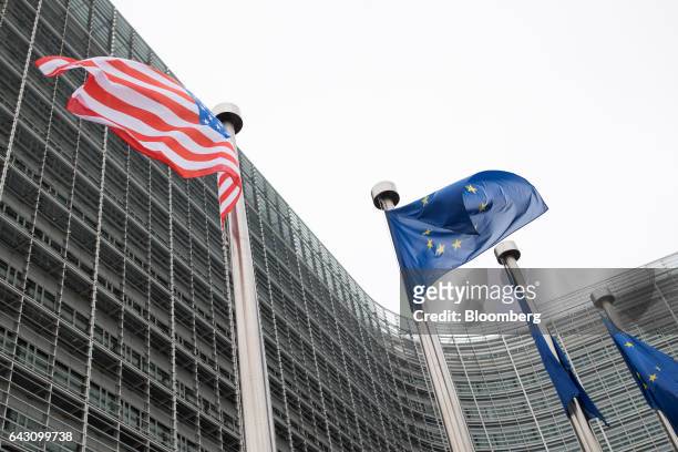The U.S. National flag, left, flies from a pole beside European Union flags outside the European Commission building following a meeting between U.S....