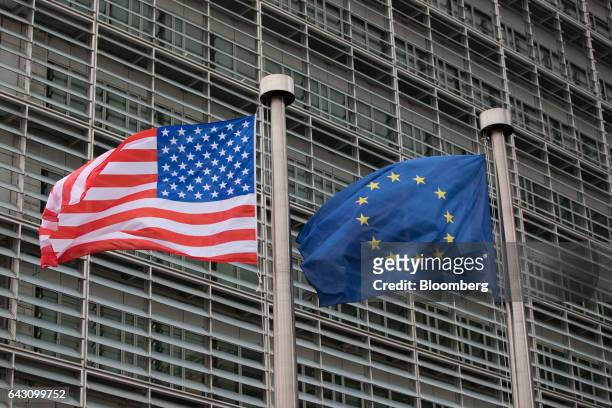 The U.S. National flag, left, flies from a pole beside a European Union flag outside the European Commission building following a meeting between...