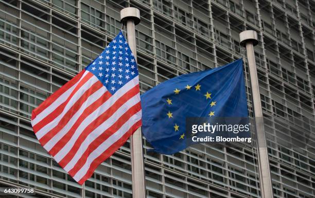 The U.S. National flag, left, flies from a pole beside a European Union flag outside the European Commission building following a meeting between...
