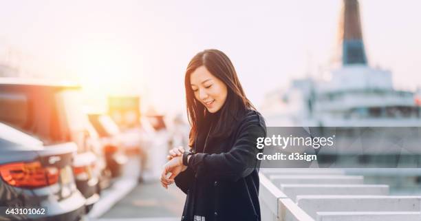 young businesswoman checking her smart watch in city by the cruise terminal - asian and indian ethnicities smartwatch phone stock pictures, royalty-free photos & images