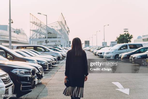 woman walking in an outdoor car park - car in car park stock pictures, royalty-free photos & images