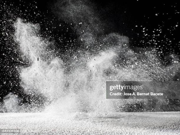 blackground of particles of white powder in ascending movement floating in the air produced by an impact - powder explosion stock pictures, royalty-free photos & images