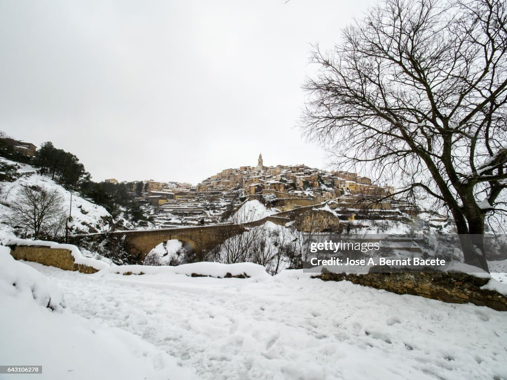 Ancient people of medieval construction snowed in winter, placed on a hill with a bridge of access