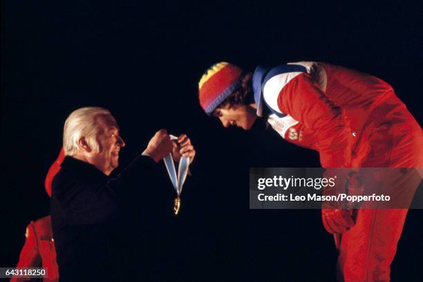 Eric Heiden of the USA bends to receive the gold medal from the International Olympic Committee President Lord Killanin after winning the men's...