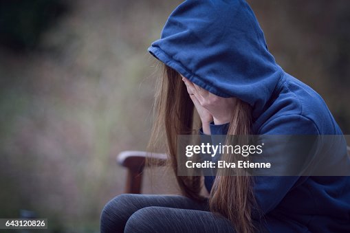 Teenage girl in hooded top, with head in hands in despair Teenage girl in hooded top, with head in hands in despair