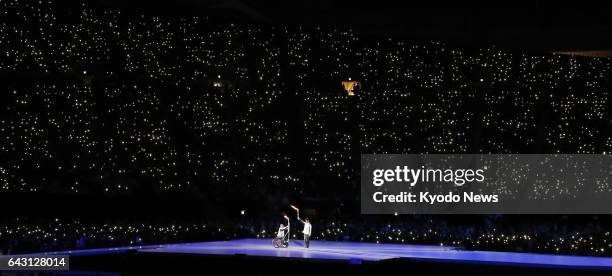 Mitsuru Nagase , the para ice hockey silver medalist in the 2010 Vancouver Paralympics, passes the sacred flame to 1998 Nagano Olympics gold...