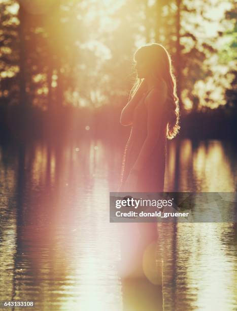 pensive young woman wading in lake at sunset - curls girl silhouette stock pictures, royalty-free photos & images