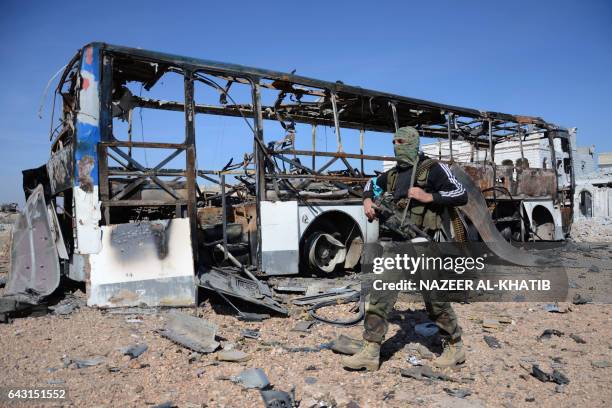 Rebel fighter, part of the Turkey-backed Euphrates Shield alliance, walks past a burnt bus as they advance on February 20 towards the city of Al-Bab,...