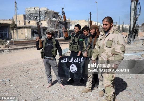 Rebel fighters, part of the Turkey-backed Euphrates Shield alliance, pose with an Islamic State group flag as they advance on February 20 towards the...