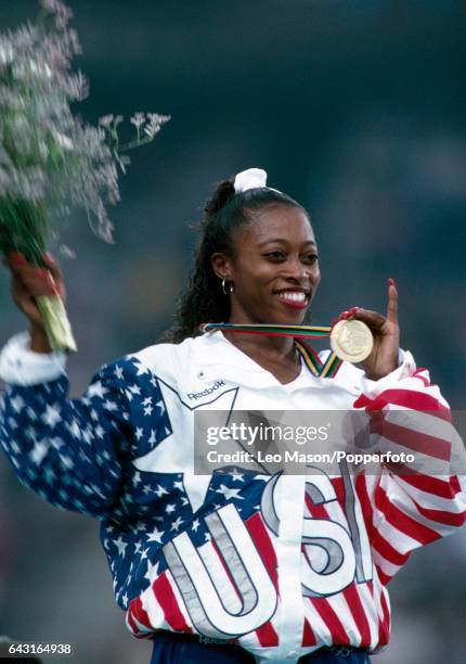 American track and field athlete Gail Devers of the United States team on the medal podium after crossing the finish line in first place to win the...