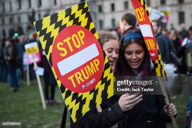 Protesters look at their phones as they hold placards during a rally in Parliament Square against US President Donald Trump's state visit to the UK...