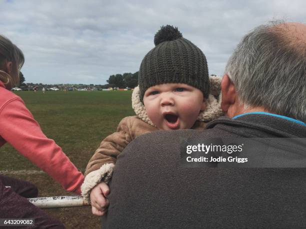 young child leaning over grandfathers shoulder yawning - bobble hat stock pictures, royalty-free photos & images