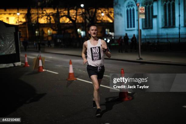Runner wearing a vest which reads 'No State Visit' jogs around Parliament Square as thousands rally against US President Donald Trump's state visit...