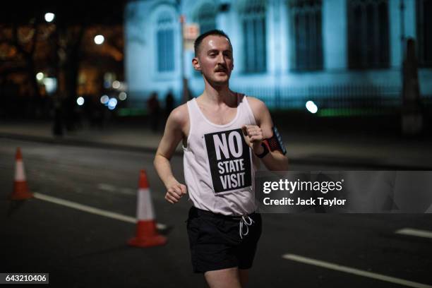 Runner wearing a vest which reads 'No State Visit' jogs around Parliament Square as thousands rally against US President Donald Trump's state visit...