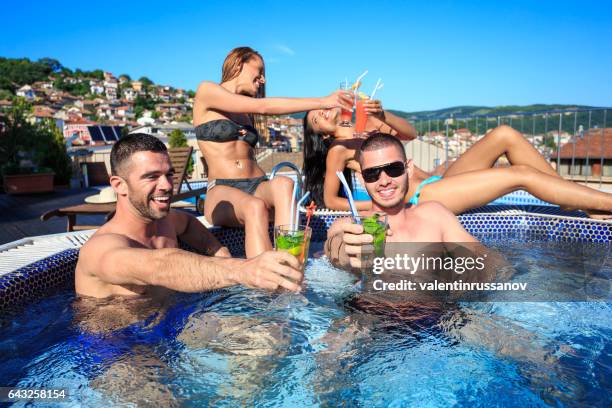 four friends drinking cocktails on rooftop swimming pool - hot tub party stock pictures, royalty-free photos & images